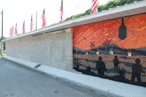 photo of a veteran memorial wall with bricks engraved with military records and a wall with a military mural.